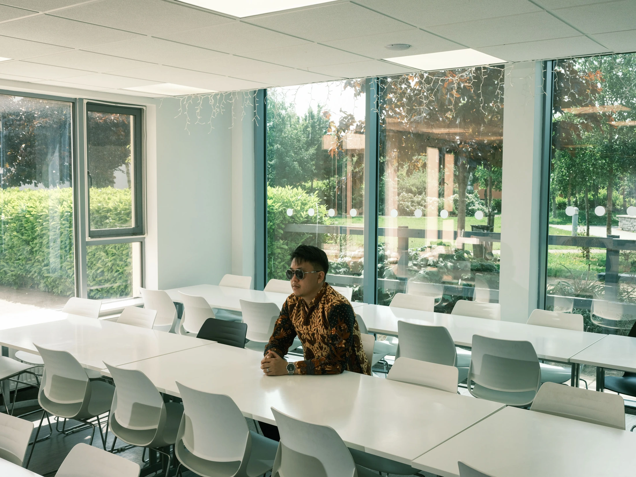 Gabe seated alone among white tables and chairs in a bright room