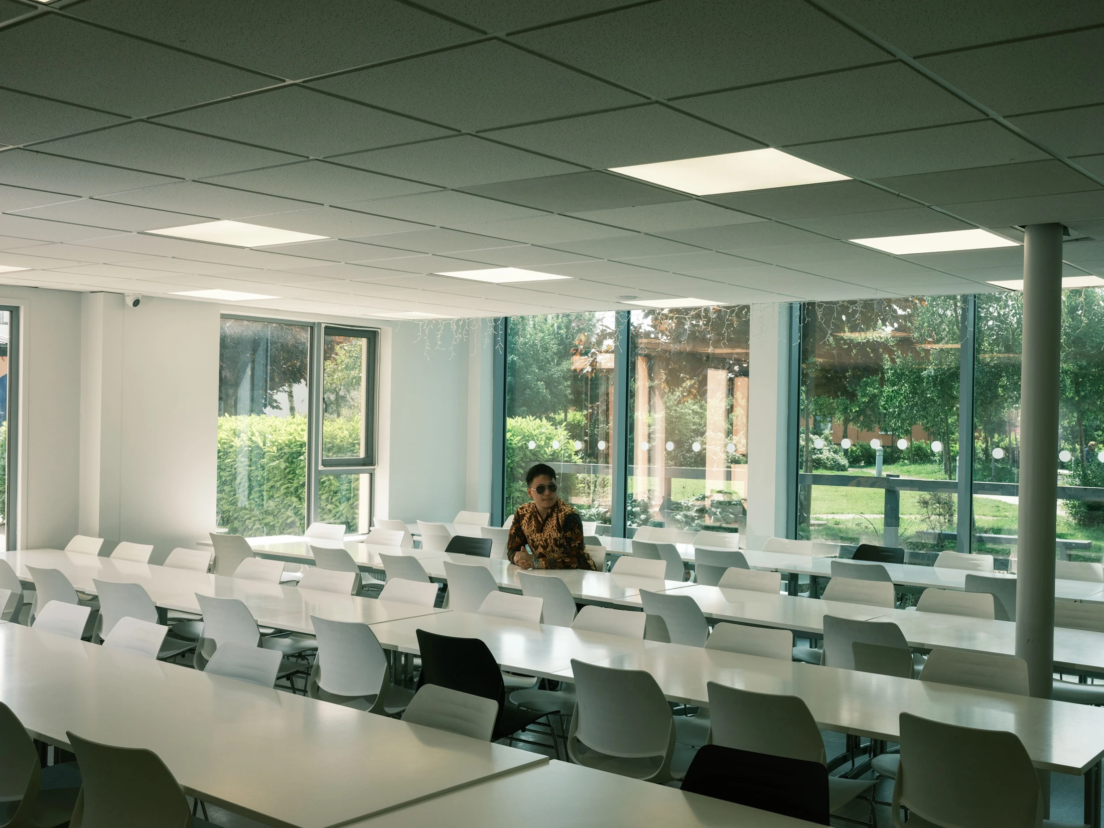 Gabe seated at the far end of a broad room of white tables and chairs