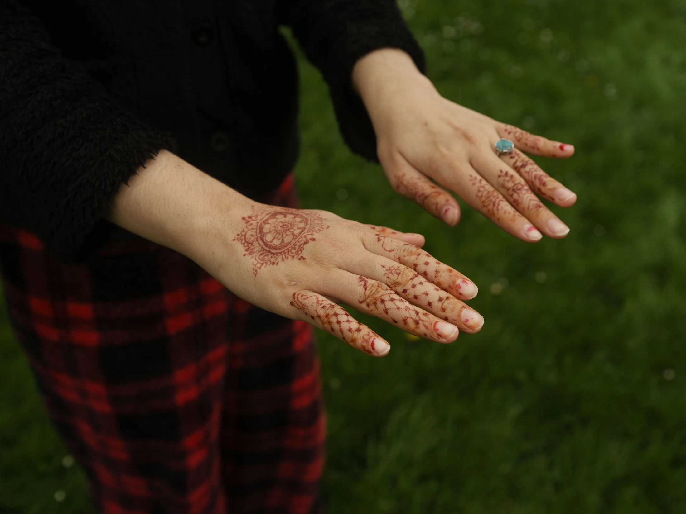 Henna-decorated hands held out above the grass