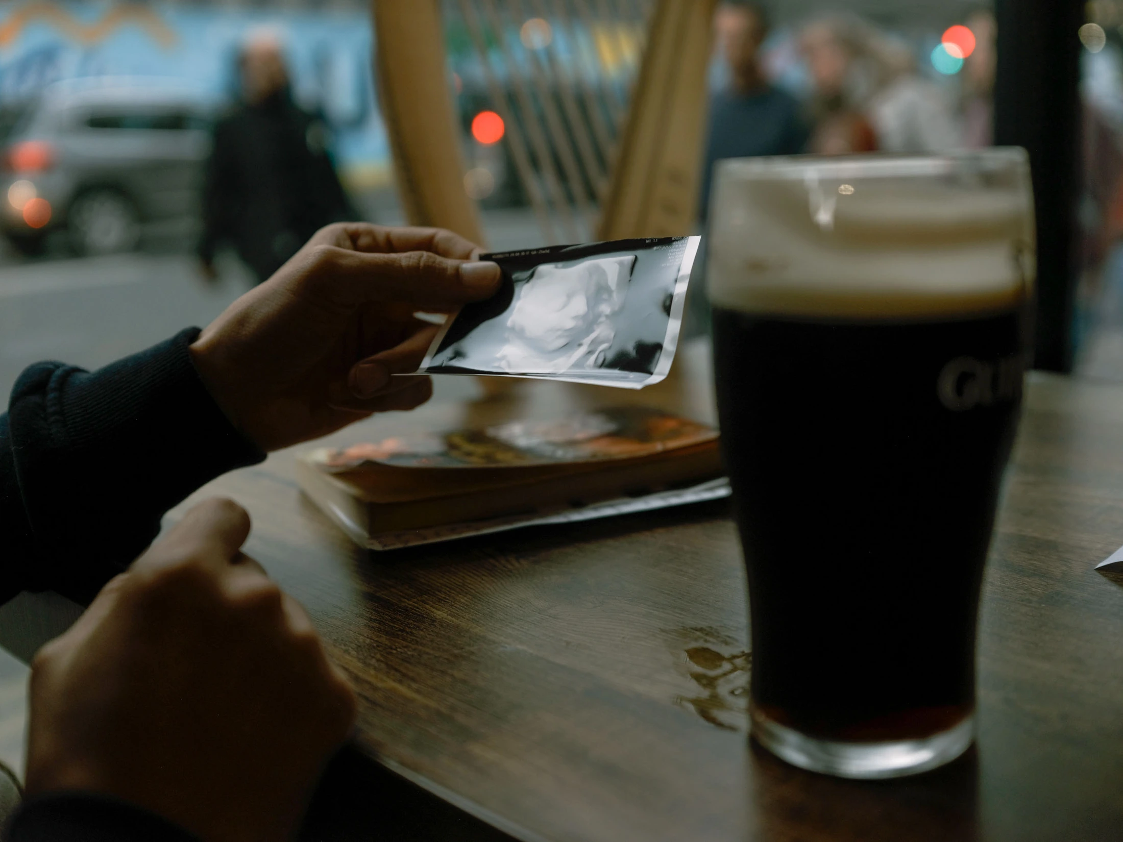 Hands holding a small photograph beside a pint glass in a pub