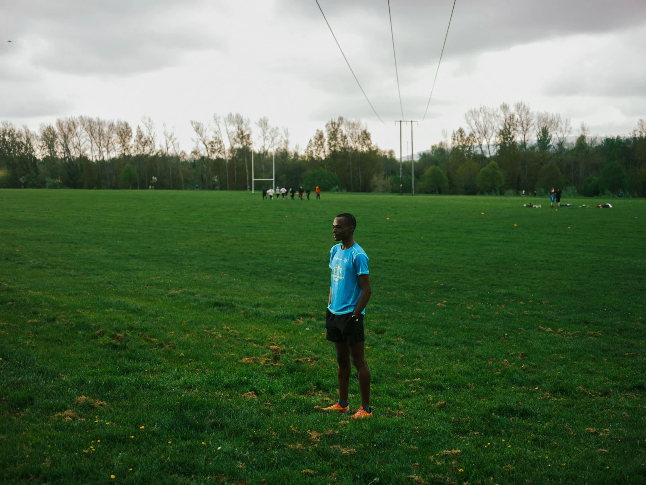 Kahumburuka standing barefoot on a broad green playing field