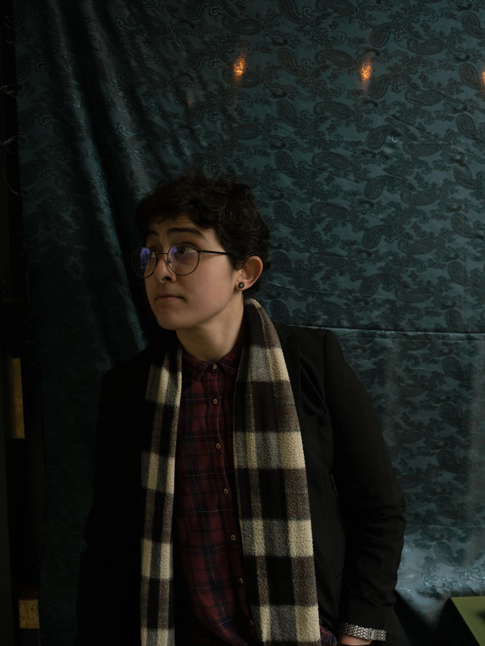 Portrait of Levant wearing glasses and a scarf against dark fabric