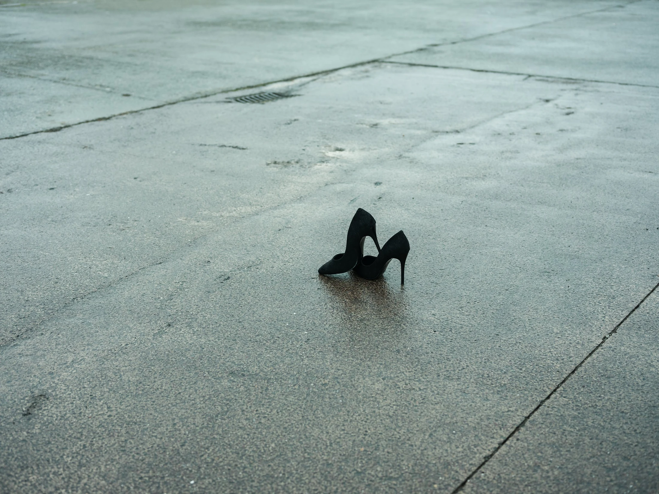 Black heeled shoes standing on pale pavement